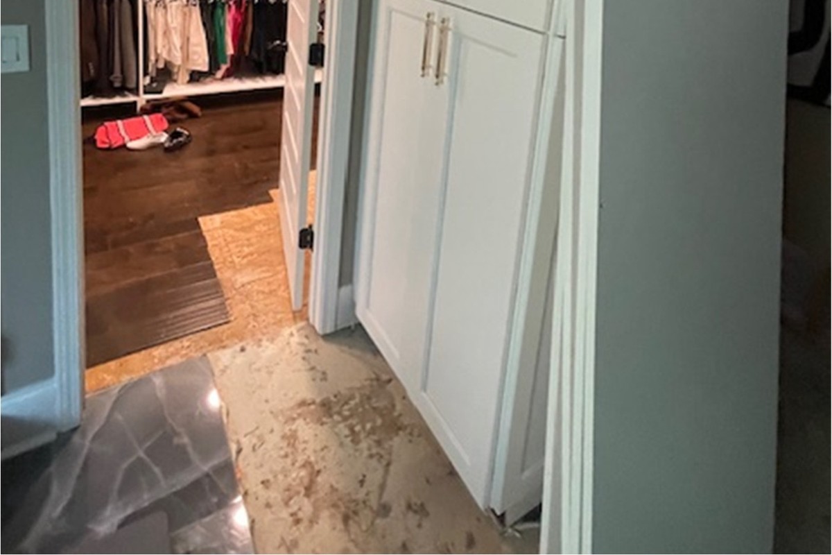 Tile removed at a master bathroom threshold where water tracked beneath the flooring