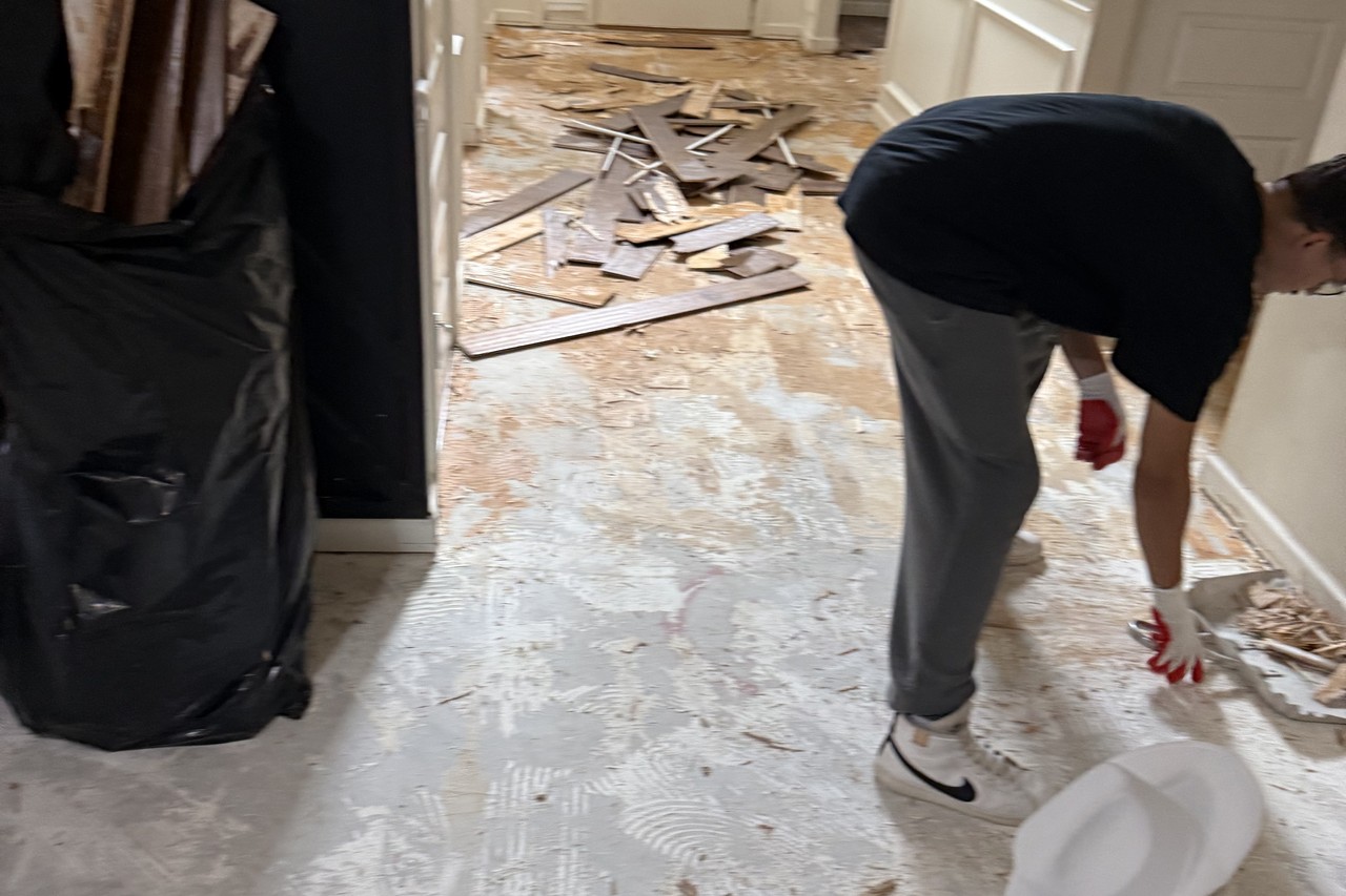 Technician bagging water-damaged flooring debris during mitigation