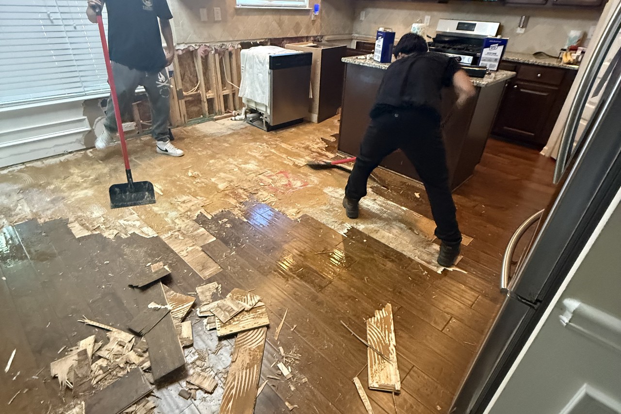 Buckled hardwood floor being removed after water damage in a Gwinnett County kitchen